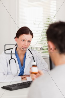 Female doctor looking at patient with pills