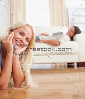Portrait of a woman lying on the floor while her fiance is with a book