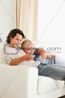 Portrait of a laughing couple cuddling while watching TV