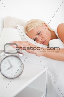 Portrait of an unhappy woman awaken by an alarmclock