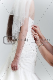 bride with long dark hair getting dressed on her wedding day - isolated on gray