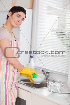 Woman washing the dishes looking into the camera