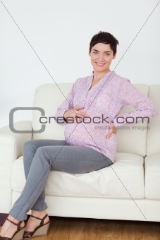 Smiling pregnant woman sitting on a sofa