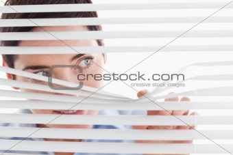 Charming businesswoman peeking through a venetian blind