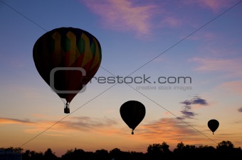 Hot-air balloons floating against a reddish dawn sky