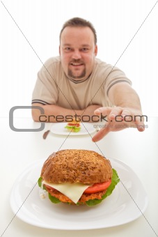 Man with small hamburger reaching for a bigger one
