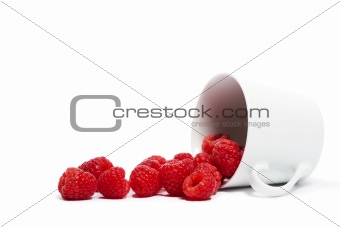 raspberries rolling from a fell over cup
