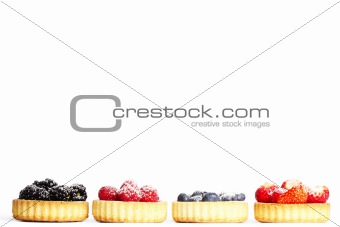 row of tartlets with sugar covered wild berries