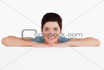 Smiling woman relying on a blank panel