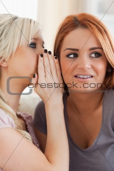 Young cute woman telling her friend a secret