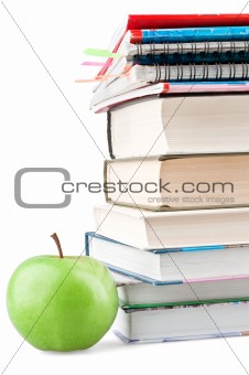 Textbooks and notebooks next to the green apple