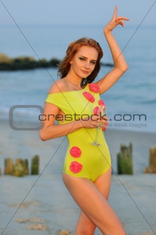 Beautiful woman with glass of champagne dancing on the beach in lime color designer's swimsuit