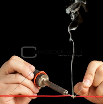 Technician bonding two wires with a solder joint.