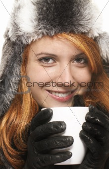 smiling young redhead woman in winter dress holding coffee cup 