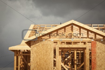 Home Construction Framing with Ominous Grey Clouds Behind.
