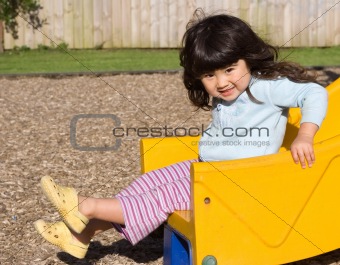 Little girl smiling and sliding on children's chute