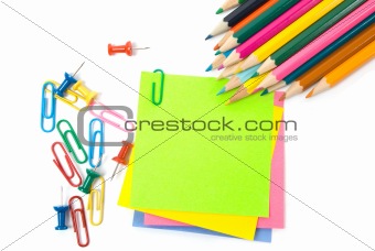 Colored pencil, clips and note paper on white