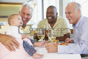 Man Showing His Baby Granddaughter To Friends At A Restaurant