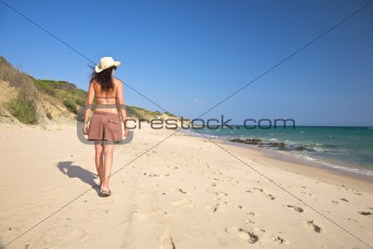 woman with hat walking beach