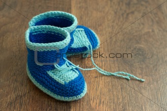 Knitted handmade baby's bootees on wood floor