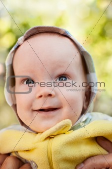 Happy baby boy on mother hands looking up