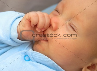 Baby boy sucking thumb to fall asleep