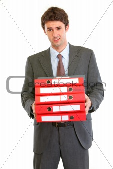 Displeased modern businessman holding many folders
