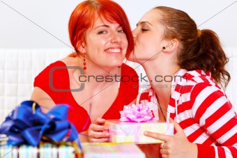 Girl presenting gift to her girlfriends and kissing her
