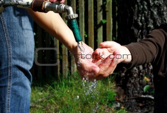 People washing ditrty hands under water stream