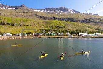 Tourist in Kayak. In background Seydisfjordur village - Iceland