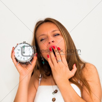Yawn-beautiful young woman holding alarm clock 