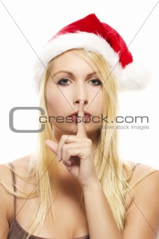 beautiful blonde woman wearing santa's hat putting finger on mouth to shhht