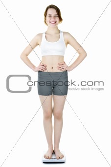 Teenage girl standing on bathroom scale smiling