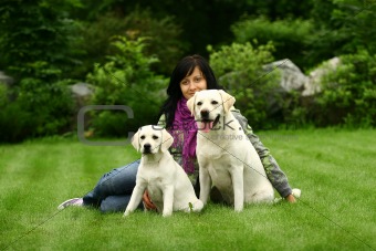 The girl sits on a grass with two dogs