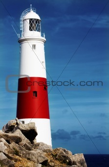 Lighthouse on rocks with blue sky