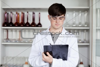 Male scientist writing on a clipboard