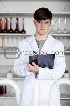 Portrait of a male science student writing on a clipboard