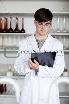 Portrait of a male scientist writing on a clipboard