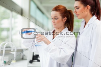 Cute scientists pouring liquid in an Erlenmeyer flask