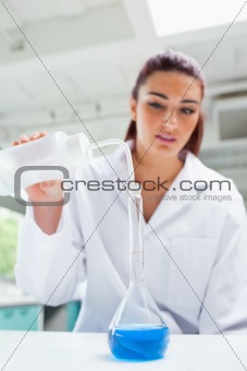 Portrait of a beautiful scientist pouring liquid