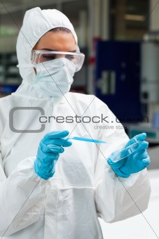 Portrait of a protected science student dropping blue liquid in a Petri dish