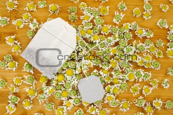 Bag of chamomile tea with dry chamomile flowers over wooden background
