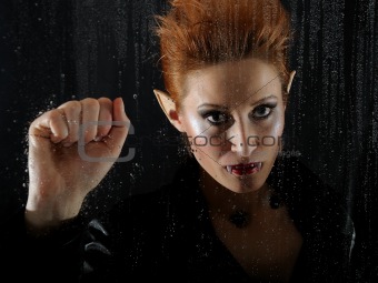 Portrait horrible fashion vampire woman behind rainy window