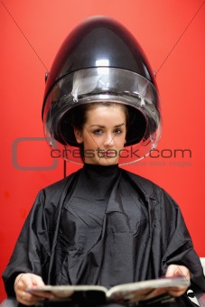 Portrait of a young woman under a hairdressing machine