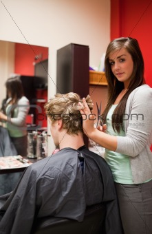 Portrait of a young woman cutting a man's hair