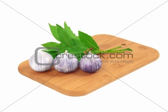 Garlic on the board with a bay leaf.