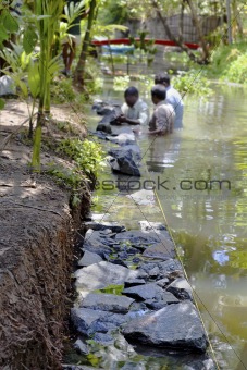 Three men underwater dry stone walling Kerala India