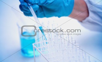 Protected hand dropping liquid in test tubes