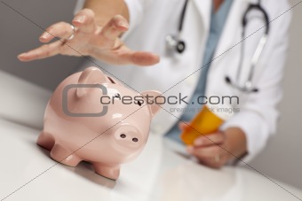 Doctor Wearing Stethoscope with Medicine Bottles Reaches for Piggy Bank.