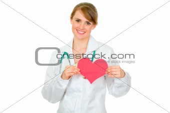 Smiling medical doctor woman holding paper heart
